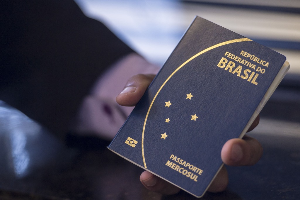 mão segurando um passaporte brasileiro